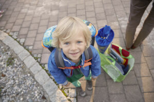 Young boy ready for school, looking up with a bright smile